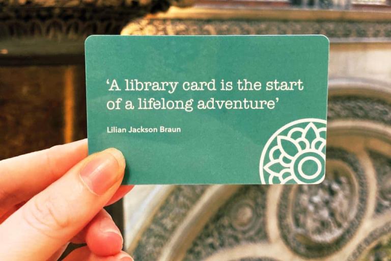 A hand holding a green library card
