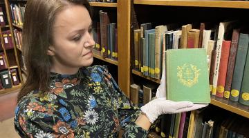 Our senior librarian Rhian Isaac holds our rare arsenic book while wearing protective white gloves