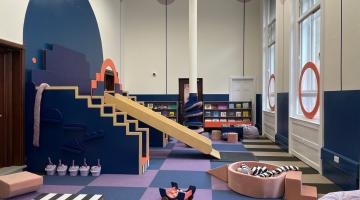 Image of a children's play area with slide, books and soft play items