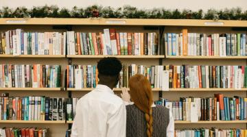 Two people seen from behind browsing shelves in a library