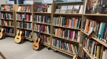 Book shelves featuring music books with guitars propped against them