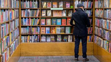 A man seen from behind looking at shelves of books
