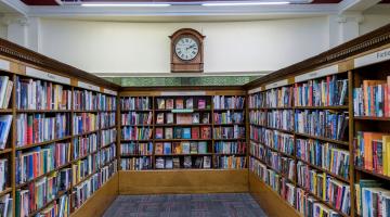 Shelves of books beneath and old fashioned clock