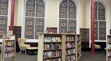 Shelves of books and beautiful tile effect wall vinyls with a seating area