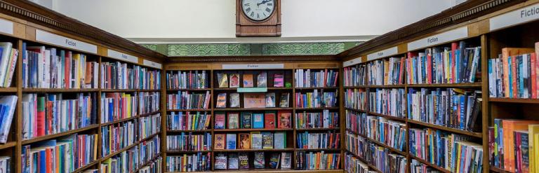 Shelves of books beneath and old fashioned clock